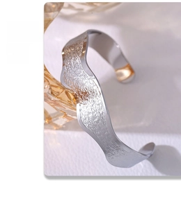 Detailed view of silver open cuff bangle with rock texture and wavy edges in bright finish