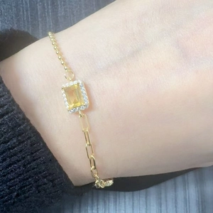 Detail of s925 silver bracelet with yellow gemstone and pavé diamonds on gold chain