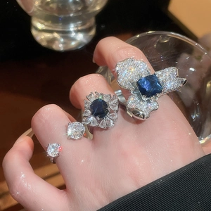 Détail d'une bague fleur de luxe avec pierres bleu foncé et zircons sur le doigt