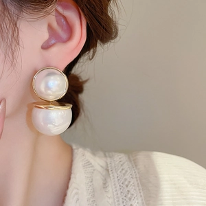 Gros plan de boucles d'oreilles élégantes en or à double perle portées par un mannequin