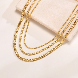 Three sizes of gold Figaro chain necklaces in 4.5mm and 6mm stainless steel on stone display