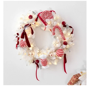 Macro view of white pine wreath featuring red candy canes and warm LED fairy lights