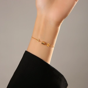 Bracelet élégant en chaîne dorée avec perle cylindre et pendentifs anneaux au poignet