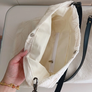 Detailed interior of beige cotton tote showing magnetic closure and floral embroidery