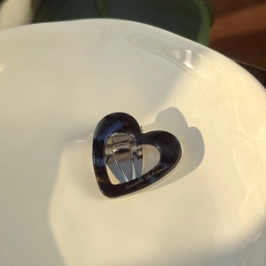 Close-up of heart-shaped tortoiseshell hair clip on white ceramic plate