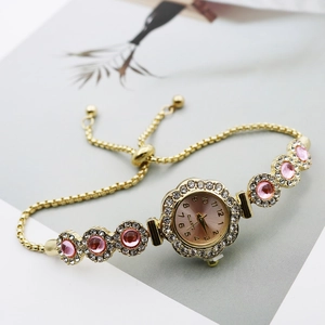 Detail of pink crystal bracelet watch featuring a petal-shaped bezel and adjustable gold chain