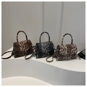Three elegant leopard print handbags in brown, silver, and beige shown on display stands