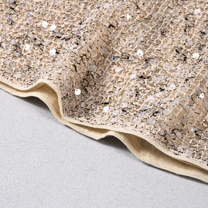 Dettaglio macro del tessuto a rete champagne con paillettes bianche e trama intrecciata