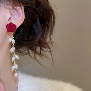 Close-up of vintage red flocked flower earrings with white pearl tassels on model