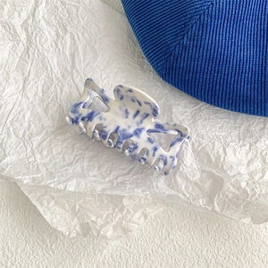 Detailed close-up of a blue and white porcelain style hair claw with marble texture