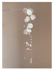 Detail of round shell pendants and white pearls hanging on a stylish tassel earring