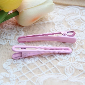 Close-up of pink gradient metal hair clips on beige lace fabric with tulip background