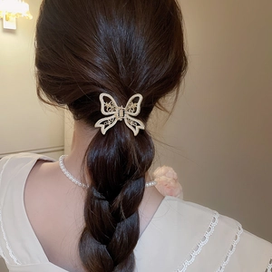 Detail of elegant gold hollow butterfly hair claw clip with pearls on long hair