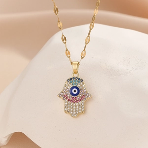 Macro shot of Hamsa hand pendant with colorful stones and evil eye on gold necklace