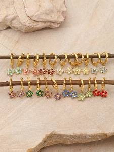 Detail of colorful birthstone flower earrings on tree branches against a stone background