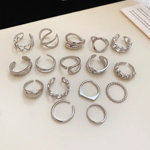 Flat lay of assorted silver irregular starfish and geometric open rings on a beige base