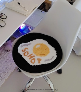 Detailed view of a soft poached egg plush cushion with SOHO embroidery on an office chair