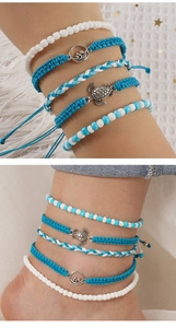 Handmade woven turtle bracelets set with blue beads and wave charms on white fabric