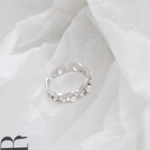 Macro detail of wave-shaped open ring with faux pearls and sparkling zircons