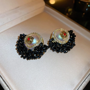 Macro detail of French vintage flower earrings with pearl, red gem and black beads