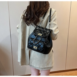 Quilted black mini backpack with chain straps and gold twist lock shown on model