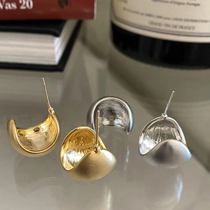 Dettaglio di orecchini a fagiolo in oro e argento con finiture in metallo spazzolato e lucido