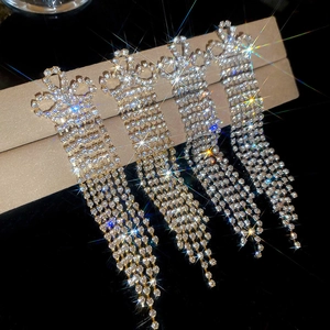 Detail view of long tassel rhinestone earrings with elegant bow design and silver finish