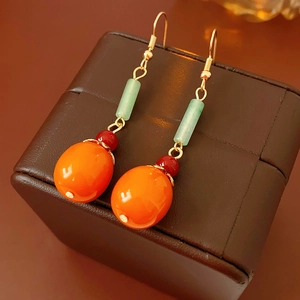 Macro detail of Persimmon pendant earrings with orange and green beads on leather base