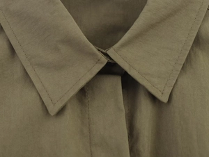 Close-up of olive green woven shirt collar with precise stitching and fabric texture