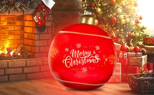 Inflatable Christmas ball with Merry Christmas print near fireplace and festive tree