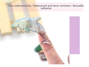 Macro shot of dolphin-shaped resin sticker with blue-pink gradient and gold foil stars