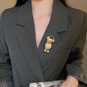 Detail of a gold bear brooch with sparkling rhinestones on a charcoal grey blazer lapel
