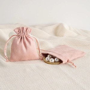 Detail of pink velvet jewelry pouch with drawstring closure on textured fabric