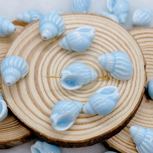 Detailed view of blue ceramic shell beads with white stripes on wooden display