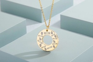 Macro view of gold round Mom pendant with rhinestones and engraved family figures