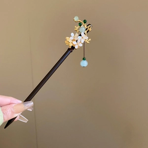 Detail of wooden hair stick with white flower, green leaves and cyan bead tassel