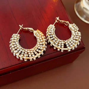 Close-up of golden rhinestone-encrusted hoop earrings on a vintage wooden gift box