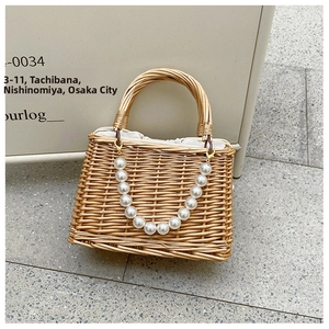 Detail of hand-woven straw bag featuring pearl chain and white drawstring inner lining