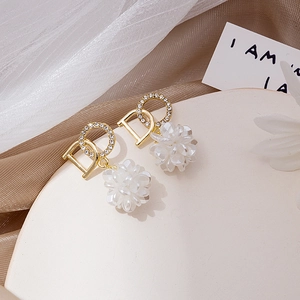 Macro view of gold hoop earrings with sparkling rhinestones and white floral pendant