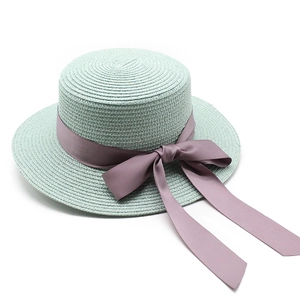Détail du tissage et du ruban de satin rose sur un chapeau de paille vert menthe