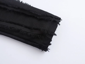 Close-up of black denim blazer coat featuring frayed edges and distressed fabric texture