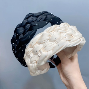 Close-up of black and beige braided satin headbands with sparkling rhinestone details