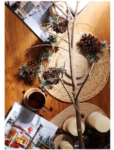 Detail of natural brown pine cone ornament with green needles and red berries for Christmas