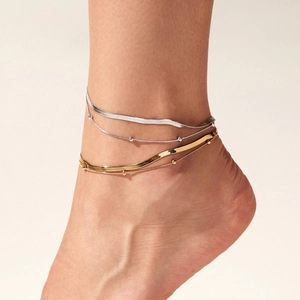Layered gold and silver stainless steel snake bone and bead anklet set on a model