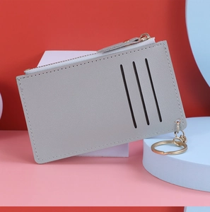 Gray leather card holder with three slots and a gold zipper pocket against a geometric background