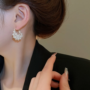 Detailed close-up of a pearl hollow flower basket U-shaped earring on a model