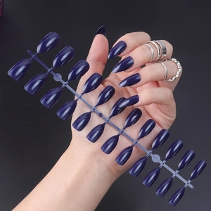 Detailed view of glossy dark purple pointed press-on nails on a plastic connector bar