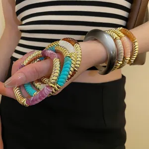 Bohemian acrylic and gold twisted metal bangle set featuring colorful textured round resin rings