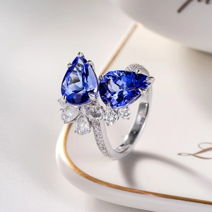 Close-up of elegant double pear-shaped blue sapphire open ring with floral diamond halo