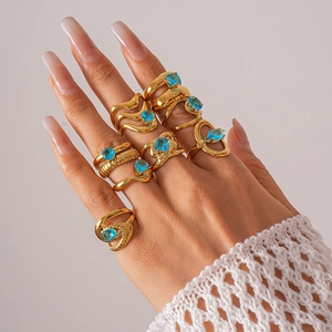 Détail de huit bagues plaquées or avec zircons bleus aux motifs texturés et ondulés